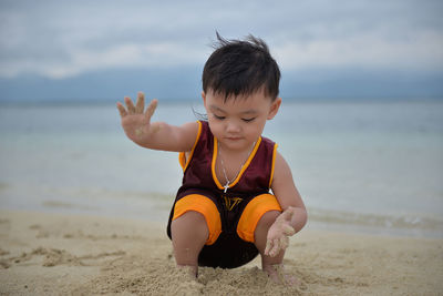 Boy playing on beach against sky