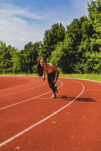 Full length of young woman at starting line on sports track