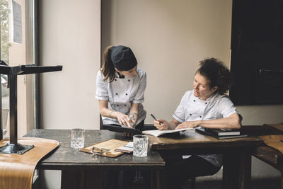 Female chefs discussing at table in restaurant