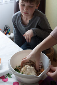 High angle view of boy looking at mother preparing food in kitchen