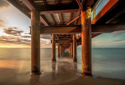 Pier over sea against sky during sunset