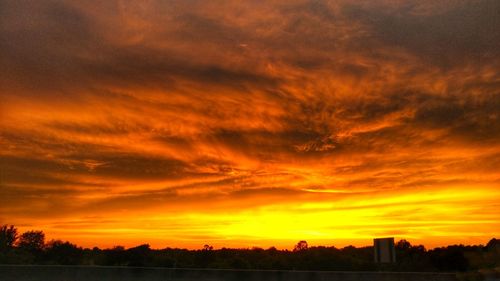 Silhouette landscape against dramatic sky during sunset