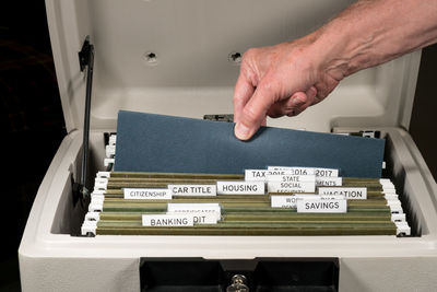 Cropped hand of man removing document from suitcase