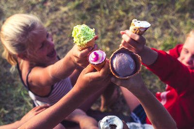 High angle view of smiling siblings toasting ice creams