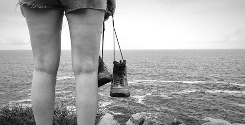 Low section of man standing in sea against sky