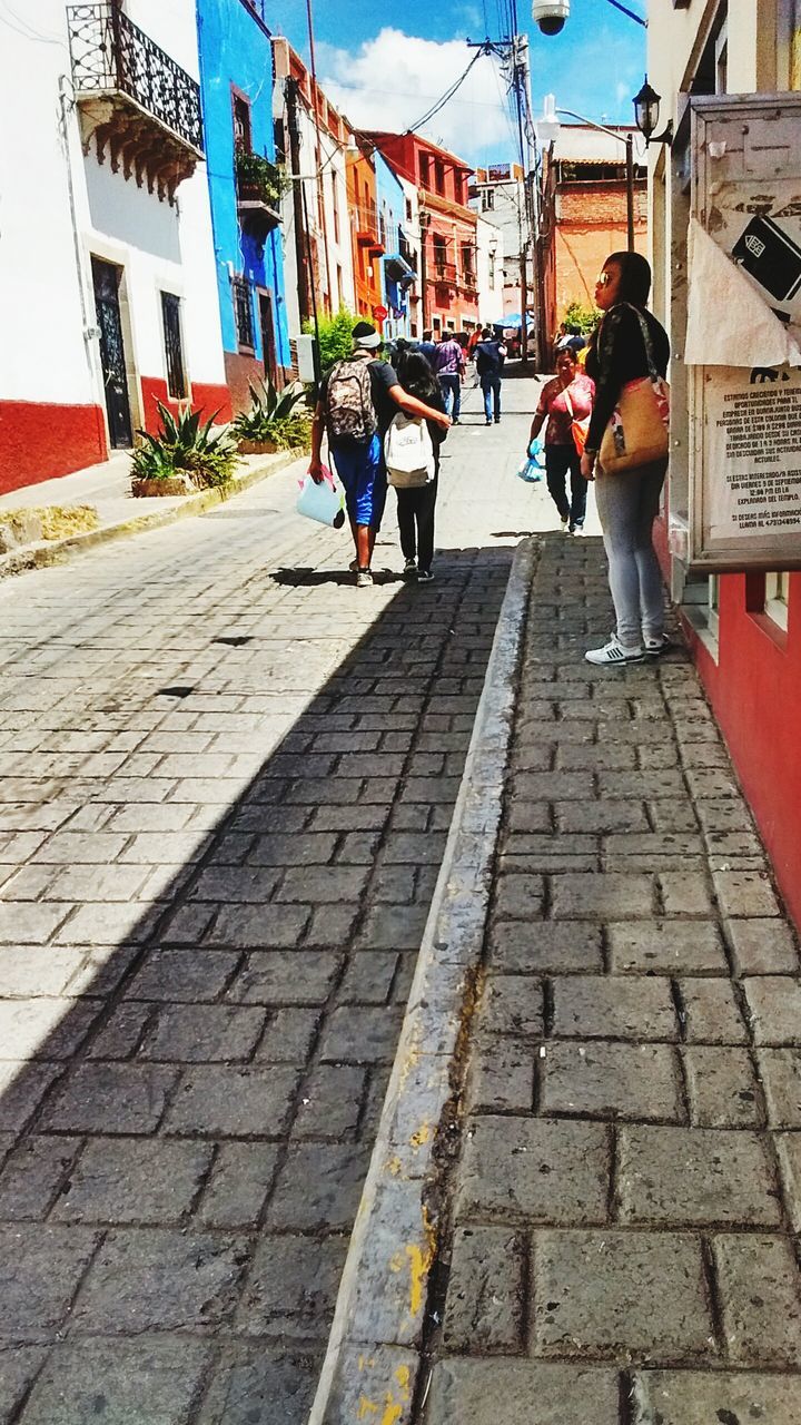 PEOPLE WALKING ON FOOTPATH ALONG BUILDINGS