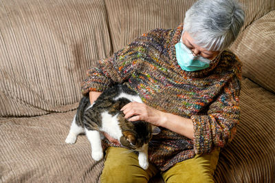 High angle view of woman with cat sitting on sofa at home