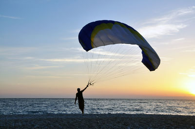 Man standing on beach against sky during sunset