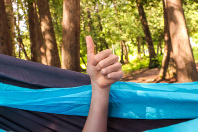 Midsection of man relaxing on hammock at forest