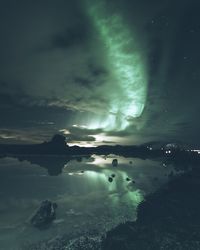 Scenic view of aurora borealis over sea against sky at night