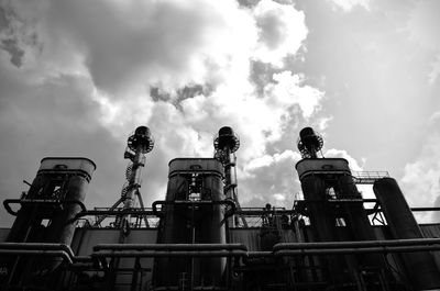 Low angle view of factory against cloudy sky