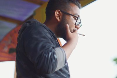 Low angle view of man smoking cigarette