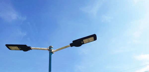 Low angle view of street light against blue sky