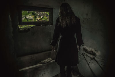 Rear view of woman standing in abandoned building