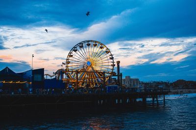 Ferris wheel in city against sky at sunset