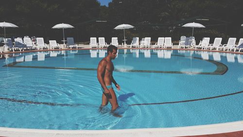 Side view of shirtless man standing in swimming pool