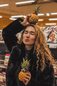 Woman with eyes closed holding pineapples in store