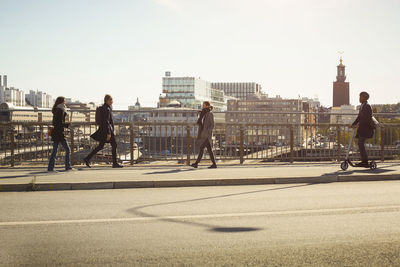 Full length of commuters on bridge in city