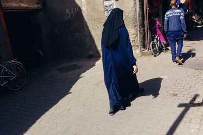 Rear view of people walking on footpath