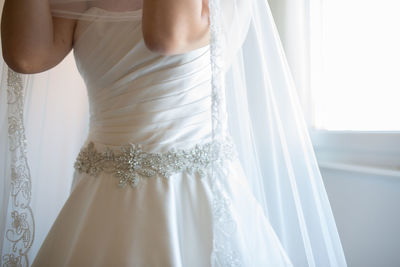 Midsection of bride standing by window