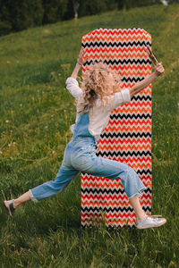 A woman in nature jumps merrily with paintbrushes in her hands