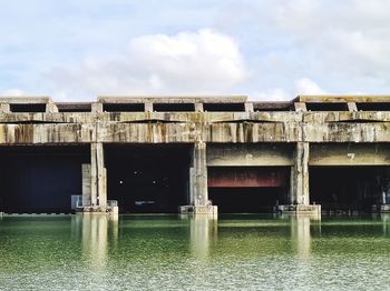 View of old building by river against cloudy sky