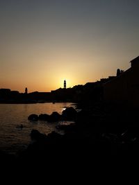 Silhouette buildings against clear sky during sunset