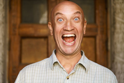 Portrait of an emotional bald guy with blue eyes. dressed in light shirt. shows