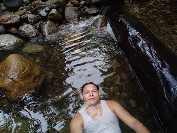 High angle portrait of man relaxing in water at forest