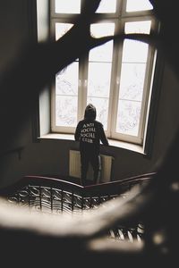 Rear view of man looking through window
