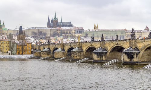 Arch bridge over river against buildings in city