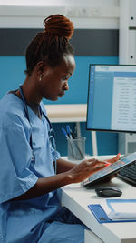 Side view of nurse using digital tablet in clinic