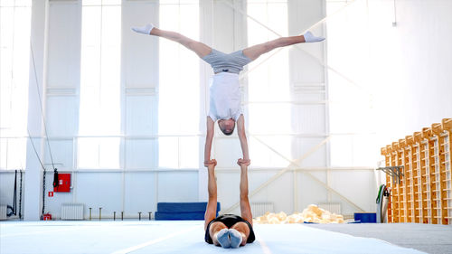 Instructor with teenage boy practicing gymnastics in club