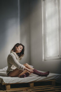 Woman sitting on window at home