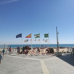 People at commercial dock against clear blue sky