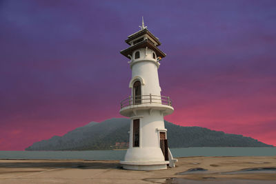 Lighthouse by sea against sky