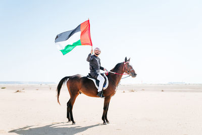 Man riding motorcycle on beach against sky