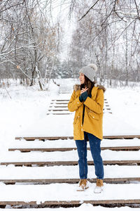 Woman standing on snow covered bare tree