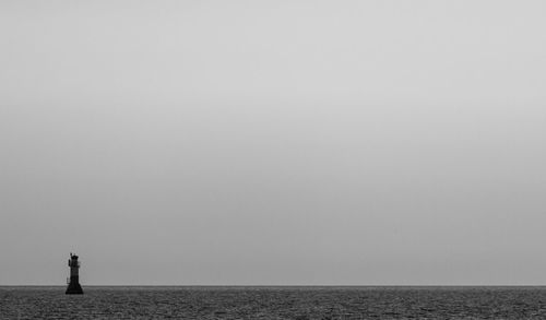 Lighthouse in sea against sky