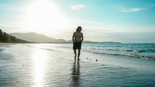 Full length of shirtless man at beach