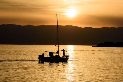 Silhouette boat sailing on sea against sky during sunset