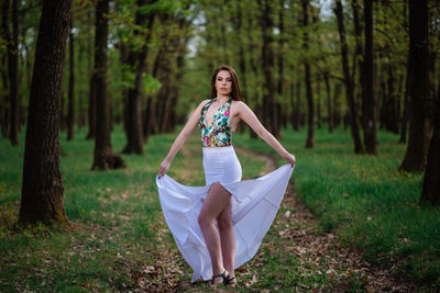 Full length of woman standing on field in forest