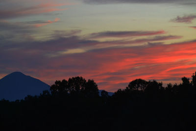 Silhouette trees against dramatic sky during sunset