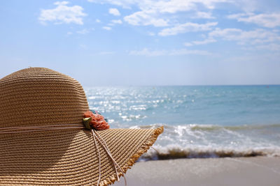 Close-up of sun hat at beach against sky