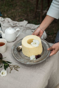 Cropped hands of woman holding cake on table