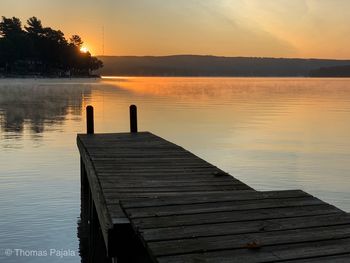 Pier on lake against sky during sunset