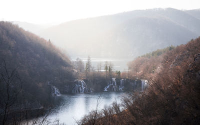 Scenic view of river by mountains against sky