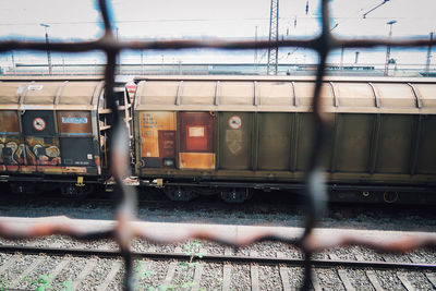 Train on railroad track seen through fence