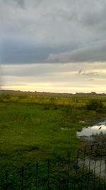 Scenic view of grassy field against cloudy sky