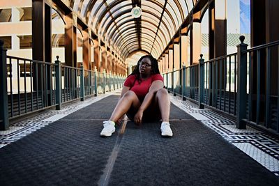 Full length of woman sitting on footbridge